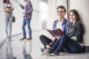 Couple students sitting and reading a book.